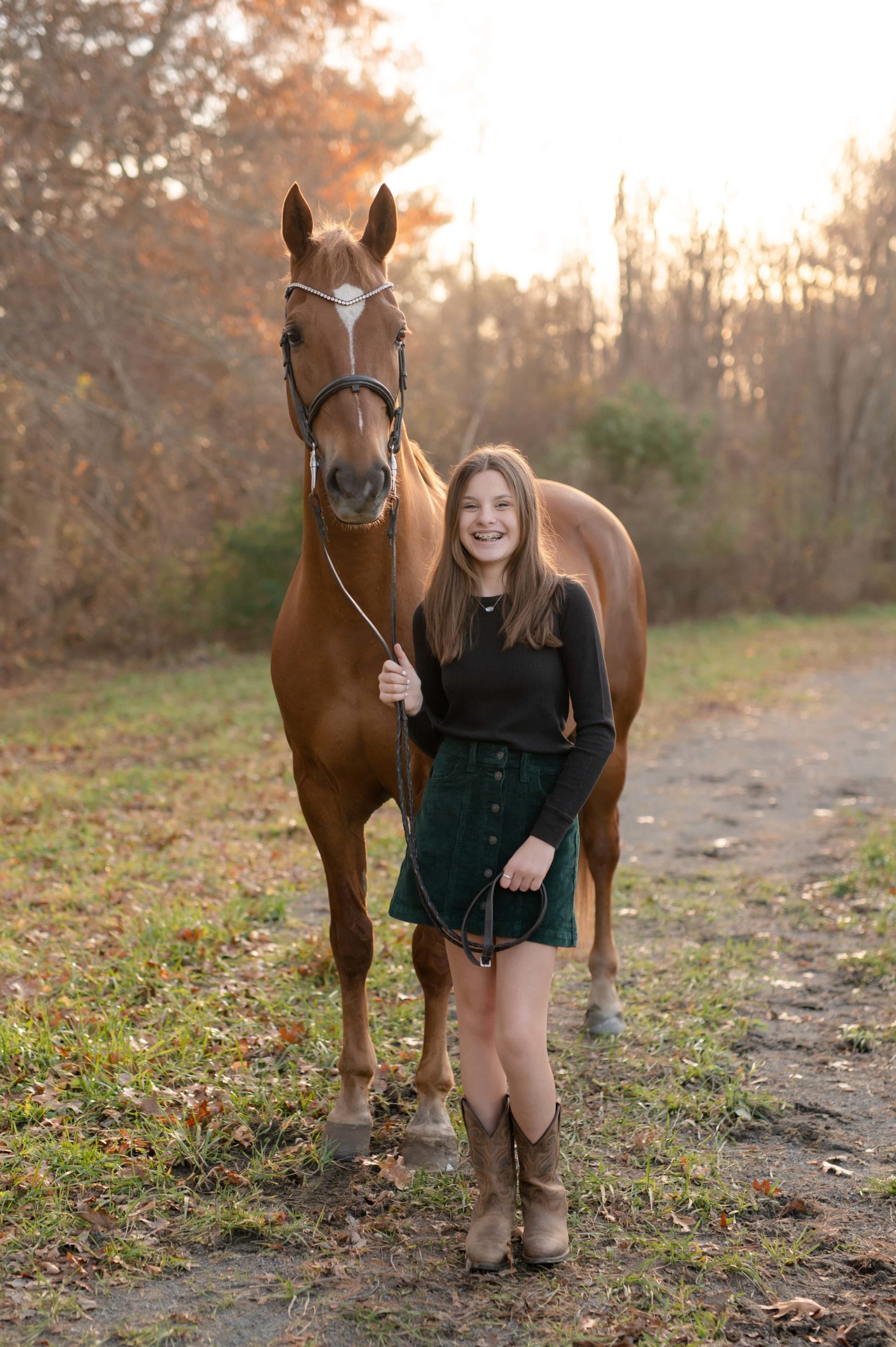 Equestrian photography with a young horse rider holding the lead line and smiling next to her horse