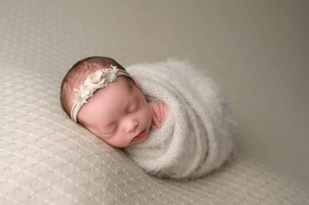 Neutral newborn photos with a linen backdrop and beige swaddle