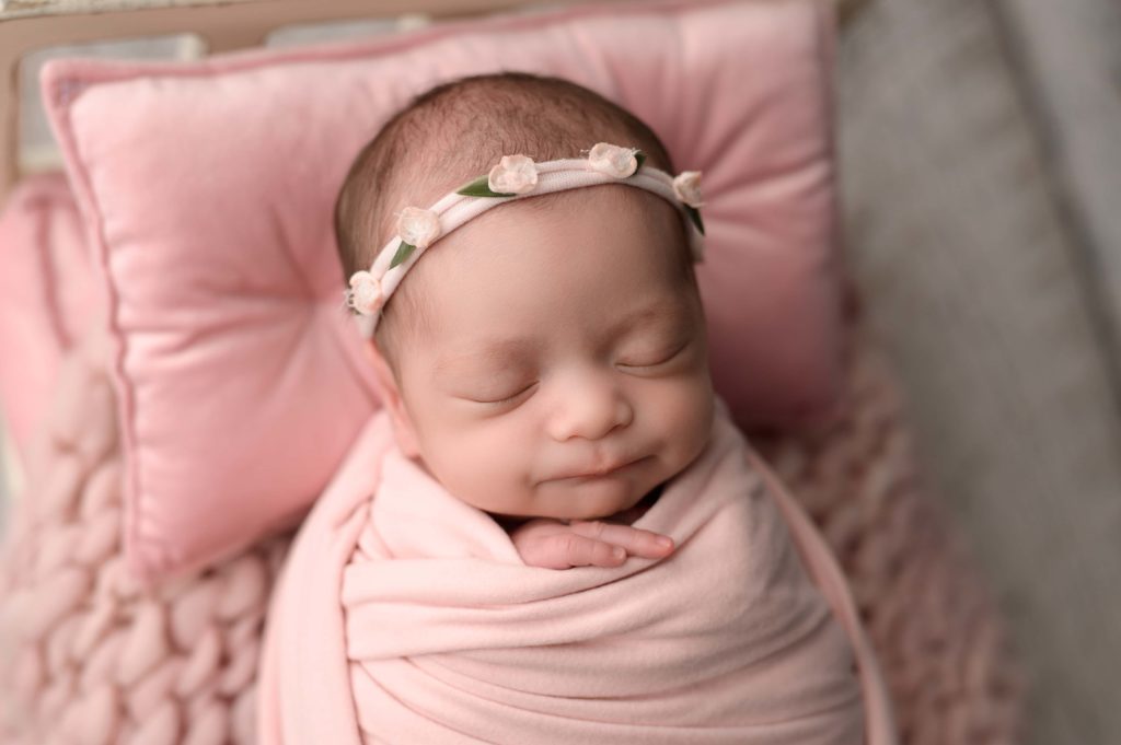Spring newborn photos with a pink swaddle and pink pillow